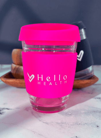 Photo of a hot pink glass coffee cup with the hello health logo on a marble counter