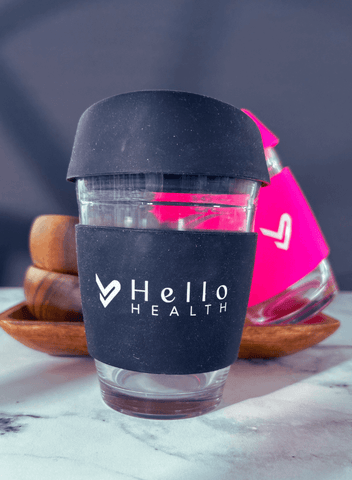 Image of the black and hot pink hello health glass coffee cups  on a marble surface 